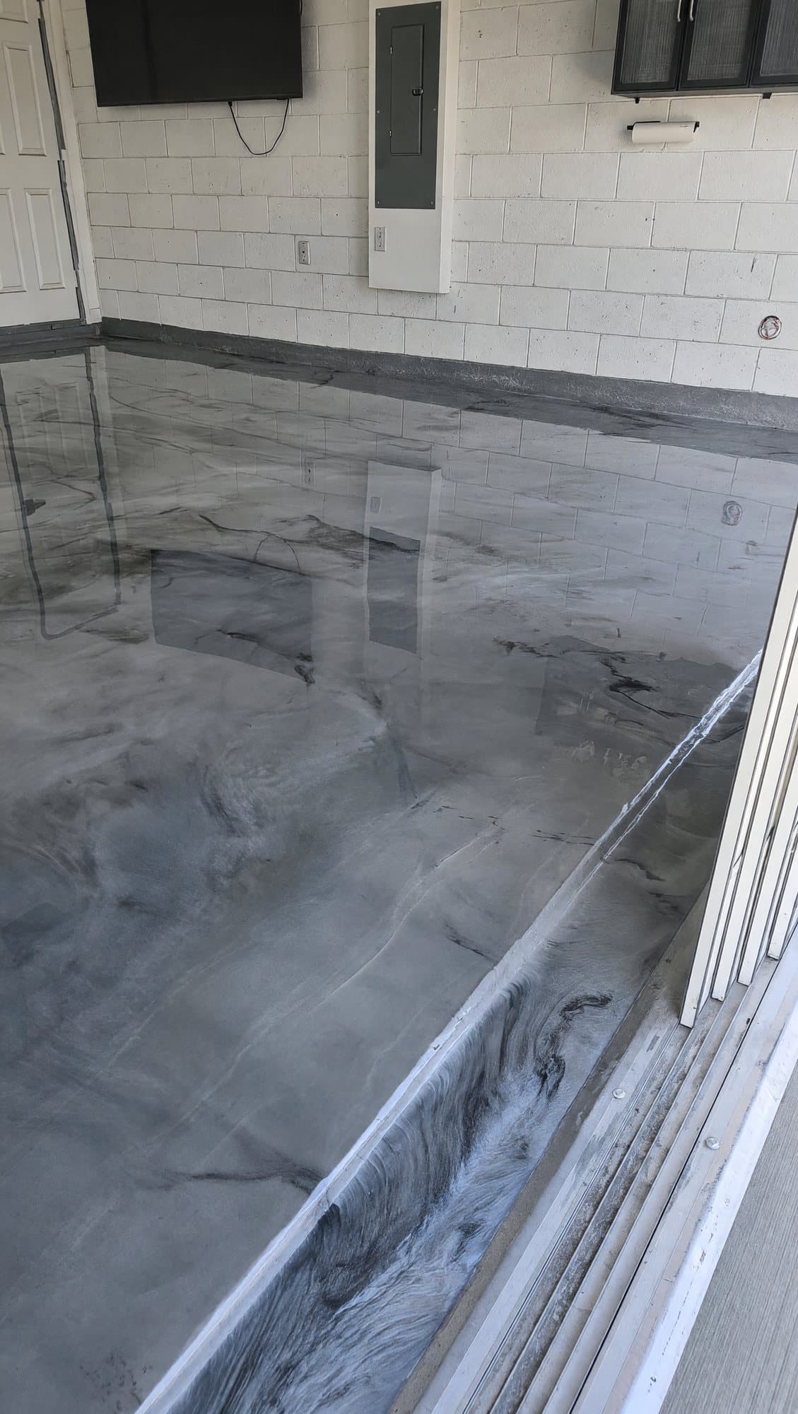 High-gloss gray and white metallic epoxy floor at a garage door threshold