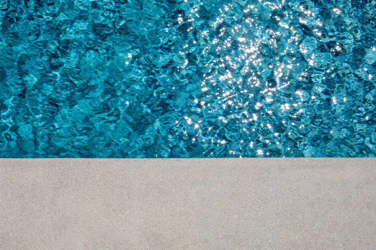 Edge of a swimming pool with a clean textured deck surface